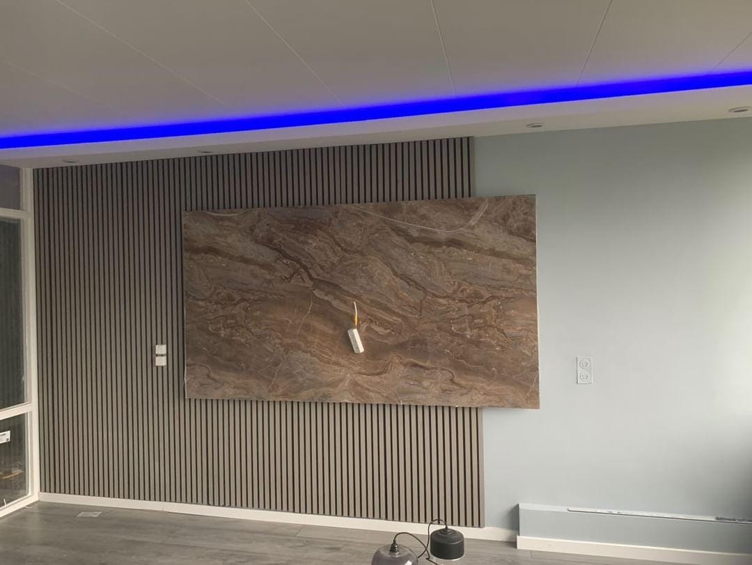 Lamellenwand met een groot paneel in steenlook en blauwe ledverlichting langs het plafond